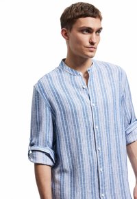 Lichte, knoopsluiting shirt met een bandkraag, met blauw en witte verticale strepen en opgerolde mouwen. Katoenmix stof.