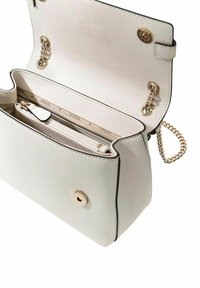 White textured handbag with gold hardware, featuring a chain strap and interior compartments, including a zip pocket and brand logo.