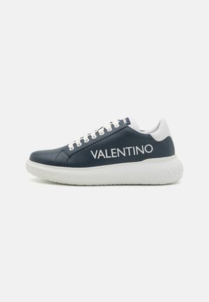 Adidași din piele bleumarin cu accente albe, prevăzuți cu o talpă groasă și un branding îndrăzneț "VALENTINO". Șireturi albe, design simplu. Siluetă plată.
