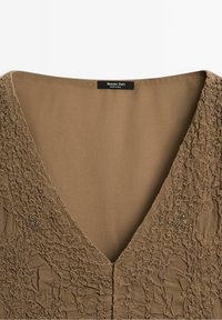 Haut en tissu marron texturé avec col en V et petites perles près de l'encolure, étiqueté Massimo Dutti, fabriqué en Inde.