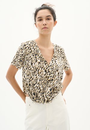 Blouse à manches courtes de couleur crème avec un motif léopard noir et marron, dotée d'un décolleté en V profond et d'une coupe décontractée. Texture lisse.
