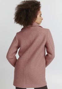 Rosa ullblandad kappa med skräddarsydd passform, bred krage och strukturerade axlar. Har en texturerad yta och sömlös ryggdesign.