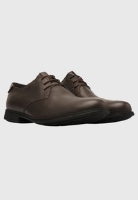 Brown leather shoes with a sleek design, rounded toe, and lace-up closures. Textured surface with a rubber sole and minimal detailing.