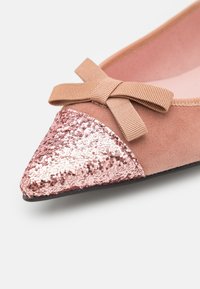 Ballerines en daim rose avec un bout pointu, dotées d'un capuchon en sequins dorés roses et d'un détail en nœud en tissu à l'avant. Doublure intérieure douce.