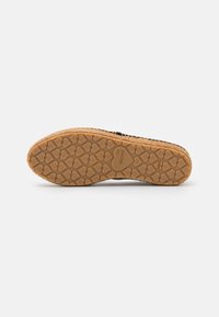 Dark-soled shoe featuring a patterned rubber outsole with heart shapes, complemented by a textured jute midsole.