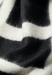Wollstoff mit modernem geometrischen Muster in Schwarz und Weiß, der eine weiche Textur mit einem subtilen, flauschigen Finish zeigt.