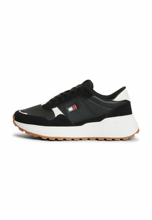 Sneaker basse bianco e nero con suola in gomma, chiusura frontale con lacci e piccolo logo rettangolare sul pannello laterale.