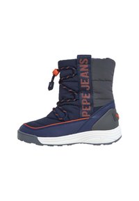 Bota de invierno azul marino con parte superior acolchada, detalles en naranja, cordones elásticos y suela blanca texturizada. Nombre de la marca impreso en el costado.