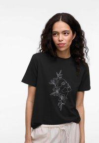 Svart bomulls t-shirt med vit konturillustration av ett ansikte omgiven av blad, kort ärm och avslappnad passform.