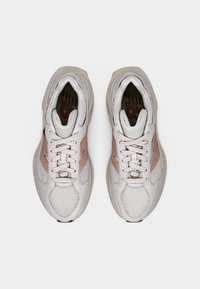 Világosszürke tornacipők hálós és velúr anyagokkal, rózsaszín részlettel, kerek orral és fűzős kialakítással. Fentről látható texturált talpak.