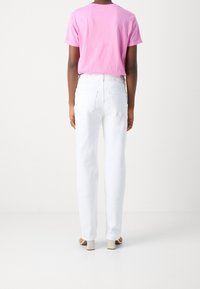 Camiseta rosa de manga corta combinada con jeans blancos de cintura alta, con un corte relajado, dos bolsillos traseros y una textura de tela suave.