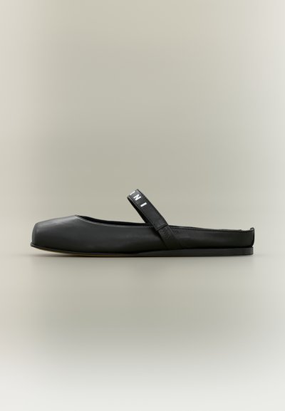 Chaussure plate noire en cuir lisse, présentant un bout rectangulaire, un talon courbé et une sangle distincte sur le dessus avec des accents de logo.
