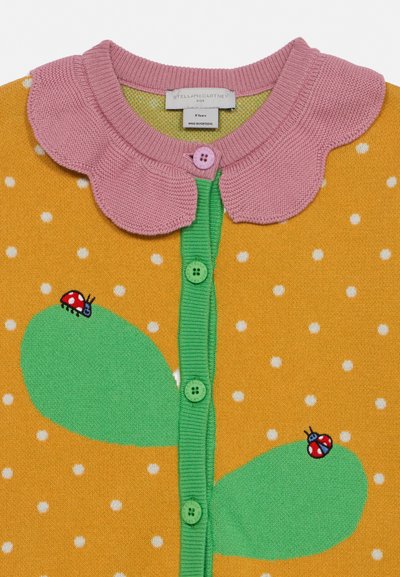 Kollane kootud kardigan valgete täppidega, rohelised nööbid ja lehed, roosa laineline krae ning lehtedel lepatriinu detailid.