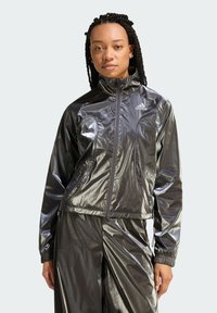 Błyszcząca czarna kurtka sportowa z wysokim kołnierzem, przednim zamkiem błyskawicznym i perforowanymi akcentami. Posiada elastyczne mankiety i dopasowany krój.