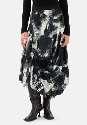 Gonna astratta in bianco e nero con design drappeggiato e tessuto testurizzato, abbinata a stivali marroni al ginocchio.