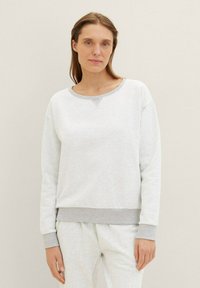 Sudadera gris clara con cuello redondo y puños grises. Tejido suave con una textura lisa; cuenta con un sutil acento triangular en el cuello.