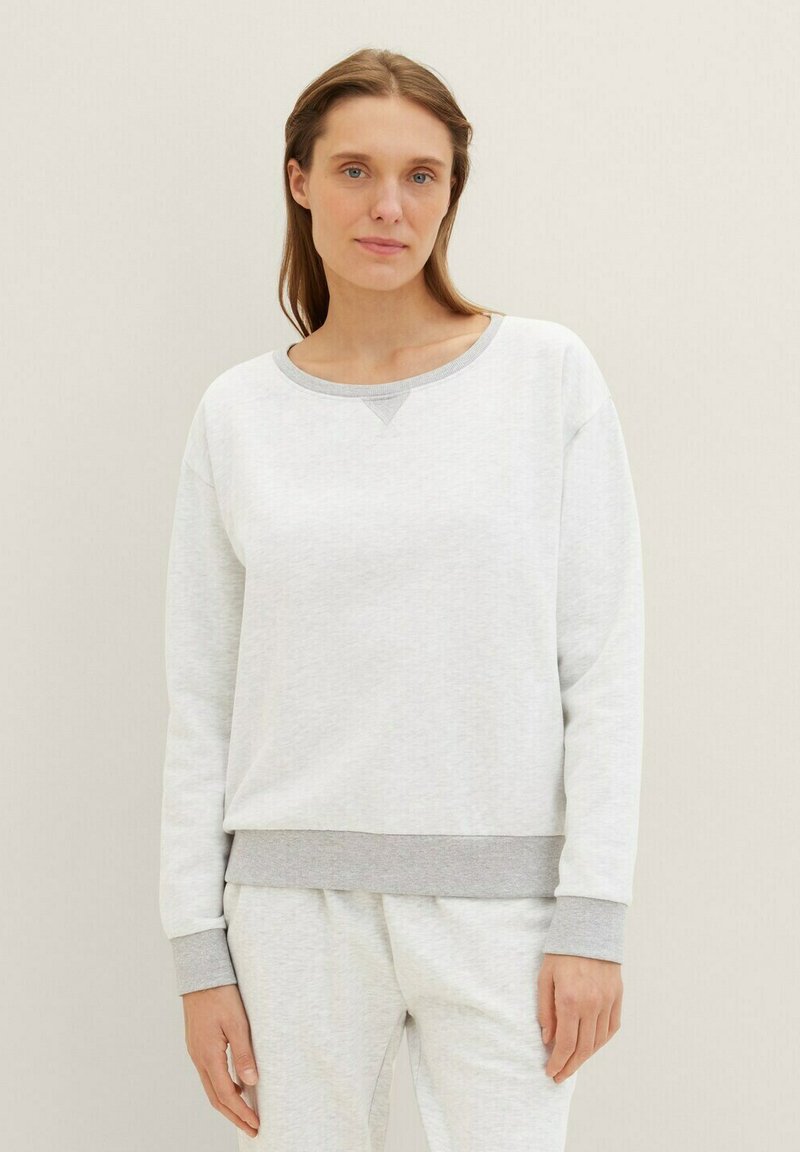 Sudadera gris clara con cuello redondo y puños grises. Tejido suave con una textura lisa; cuenta con un sutil acento triangular en el cuello.