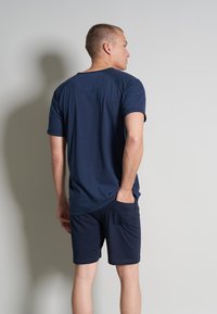 Navyblaues T-Shirt mit kurzen Ärmeln und rundem Halsausschnitt, kombiniert mit passenden Shorts mit einer seitlichen Tasche und einer lockeren Passform.