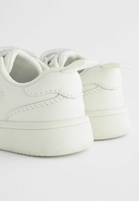 Witte sneakers met een gladde leren bovenkant, ronde neus, gevoerde schacht en een getextureerde rubberen zool. Bevat subtiele stiksels en hiel tabs.