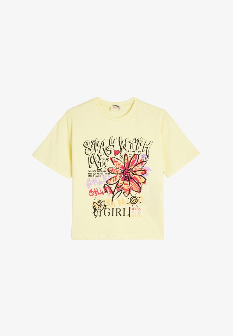 Gul kortærmet T-shirt med et stort blomstertryk og forskellige textelementer i sort, pink og lilla. Blødt bomuldsstof.