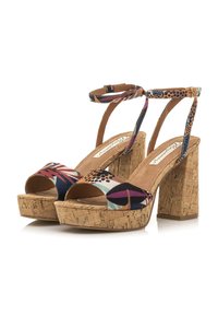 Tacones de plataforma multicolores con tacón de corcho en bloque, punta abierta y correa ajustable en el tobillo. Presenta patrones geométricos y tela texturizada.