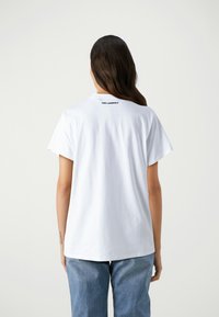 T-shirt bianco in cotone con una vestibilità rilassata, maniche corte e logo nero "KARL LAGERFELD" ben visibile sul colletto posteriore.