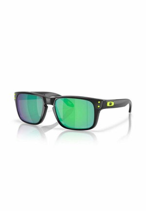 Occhiali da sole neri con montature angolari, dotati di lenti a gradiente verde. Accentuati da piccole macchie gialle sulle tempie. Finitura liscia.