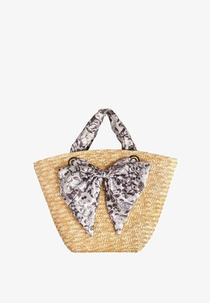 Torba od slame s velikom, teksturiranom crno-bijelom cvjetnom maramom u obliku mašne, koja ima dvije čvrste ručke i široko, otvoreno dno.