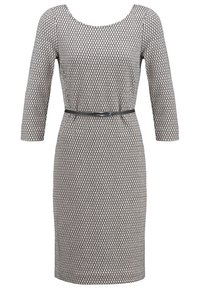 Robe à motifs en noir et blanc avec manches trois-quarts, encolure dégagée et taille cintrée soulignée par une fine ceinture.