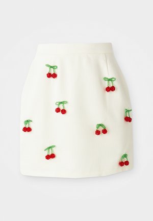 White textured skirt featuring red plastic cherry appliqués with green stems, evenly distributed across the fabric surface.