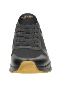 Black athletic shoe with a smooth leather and mesh upper, lace-up design, and a textured rubber sole in a contrasting tan color.