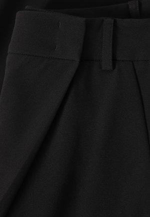 Mustad kohandatud püksid vööaasa ja volditud eesdetailiga, lähivaade vöörihmale ja ülemisele kangatekstuurile.