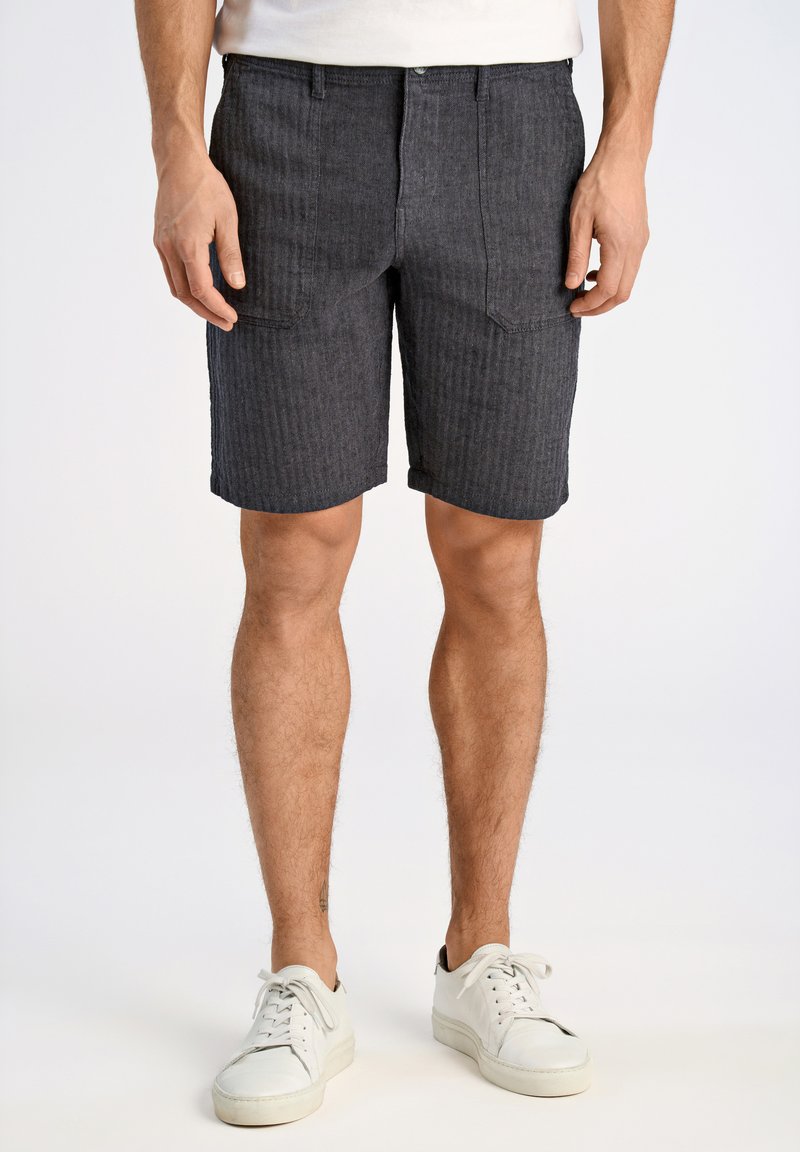 Donkergrijze gestreepte shorts van stof, met riemlussen, voorzakken en een knoopsluiting. Gecombineerd met witte sneakers.