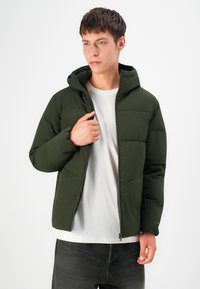 Green puffer jacket with a hood, featuring a zip front, quilted design, and elastic cuffs, worn over a light-colored t-shirt.