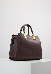 Diep burgundy leren handtas met twee handvatten bovenaan, accenten van goudkleurig metaal en een gestructureerd oppervlak. Heeft een gestructureerd ontwerp.