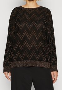 Pull noir avec motif zigzag métallique en bronze. Manches longues, encolure ronde et finition texturée aux ourlets et aux poignets.