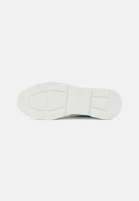 Sole di sneaker bianca con motivo di presa testurizzato, caratterizzata da ritagli rettangolari e una leggera curvatura nella punta. Design pulito e minimalista.