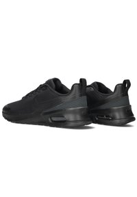Zwarte sportieve schoenen met een gestructureerde mesh bovenkant, rubberen zool en zichtbare luchtkussens in de hak. Voldoende padding rond de kraag.