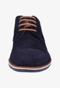 Chaussure de ville en daim bleu marine avec des lacets beige, bout perforé, bordures marron et semelle accentu ée de blanc, vue de face.