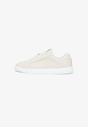 Beige lage sneaker met witte zool, vetersluiting en subtiel Tommy Hilfiger-logo aan de zijkant.