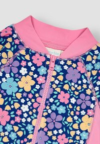 Bañador floral con base azul marino y patrones de flores en rosa, púrpura y amarillo. Incluye un cuello rosa y una cremallera en la parte delantera.