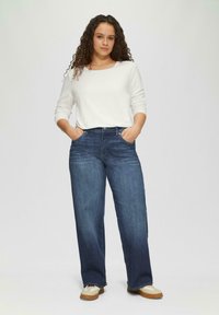 Lichtgewicht witte lange mouwen top met een wijde halslijn, gecombineerd met donkerblauwe wijde jeans, voorzien van zijzakken en een gladde textuur.