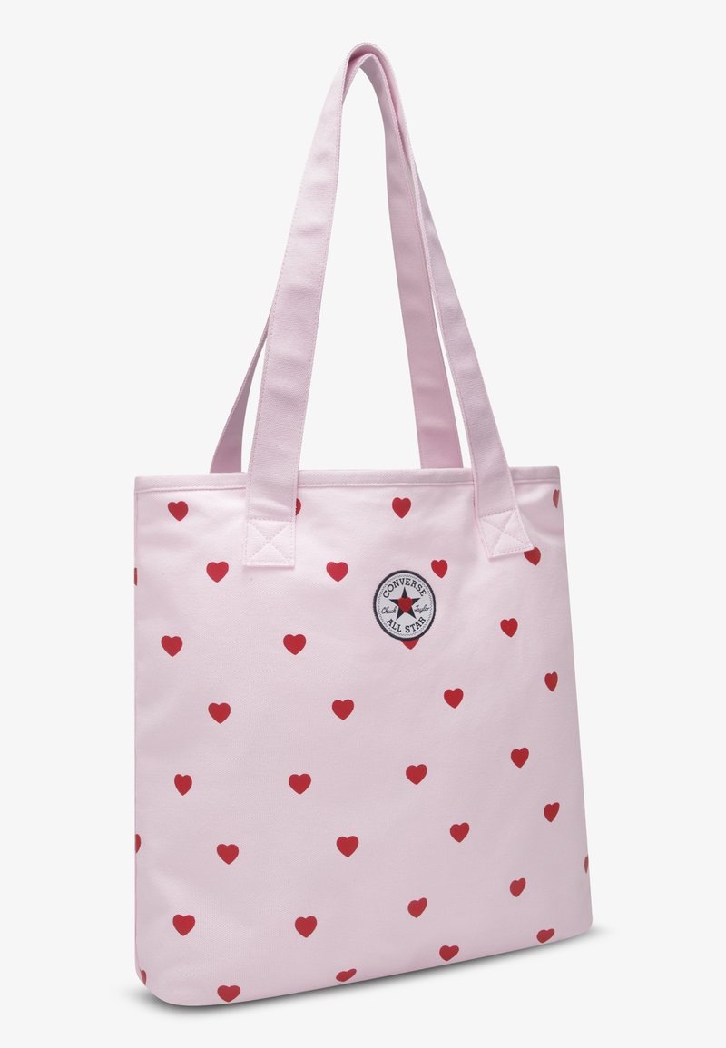 Φωτεινή ροζ τσάντα ώμου με κόκκινο μοτίβο καρδιάς, ορθογώνιο σχήμα, διπλές ανθεκτικές λαβές και κυκλικό λογότυπο Converse All Star.