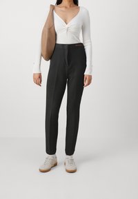 Svarta skräddarsydda byxor med en mjuk textur, hög midja och subtila sömnadsdetaljer, kombinerade med en vit ribbad långärmad topp.