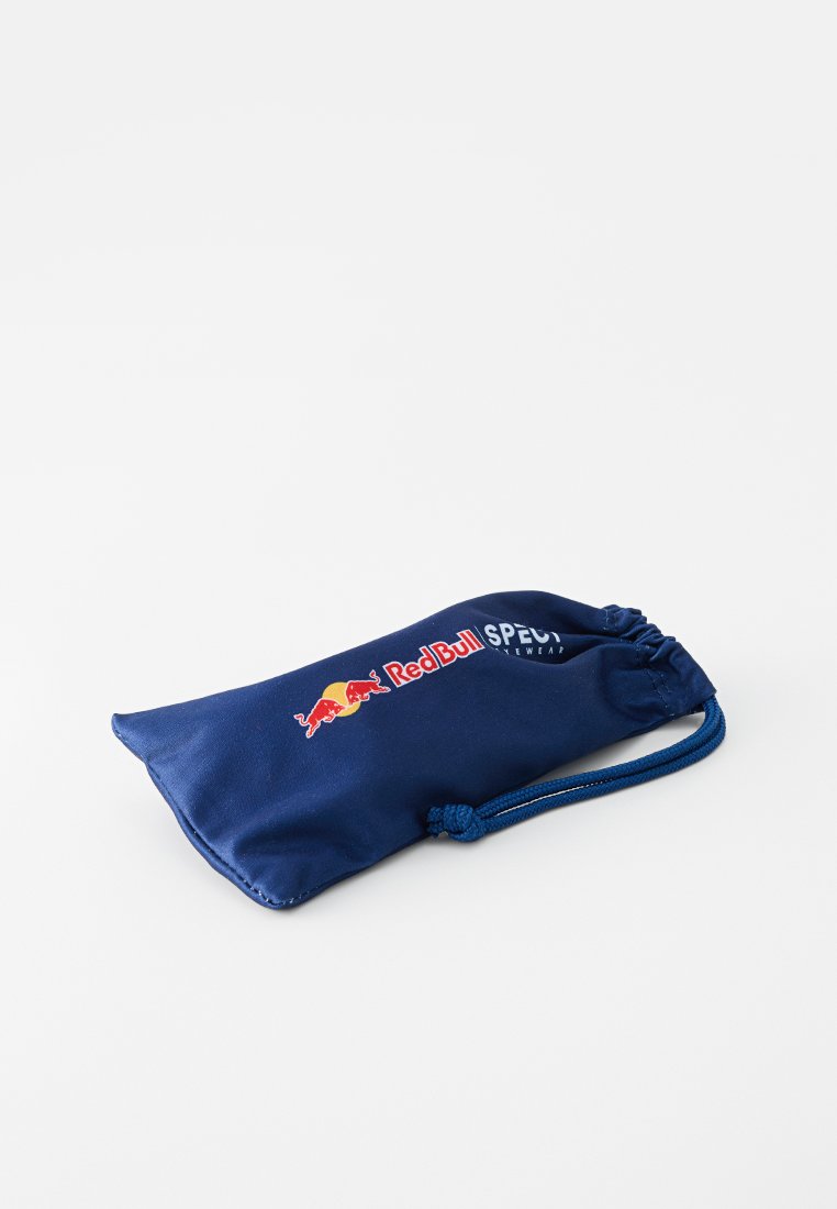 Granatowa saszetka na sznurek wykonana z gładkiego materiału, z logo Red Bull w kolorze czerwonym i żółtym, z napisem "SPEC" w kolorze białym.
