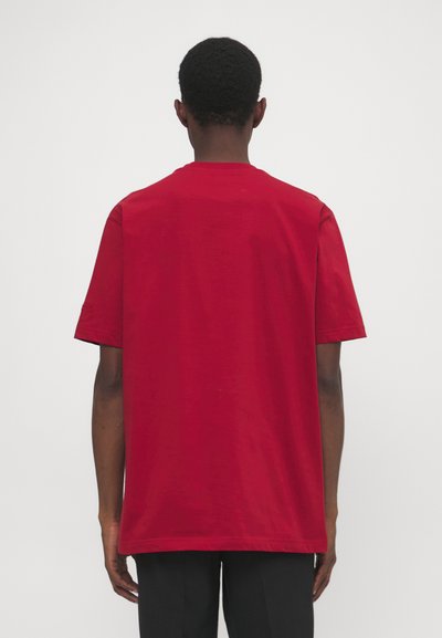 Rotes Baumwoll-T-Shirt mit kurzen Ärmeln, klassischem Rundhalsausschnitt und lässigem Schnitt. Der Stoff wirkt weich und glatt, keine sichtbaren Logos oder Muster.