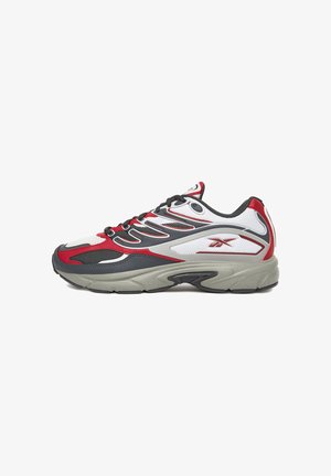 Atletski čevelj z zgornjim delom iz belega mrežastega materiala, rdečimi in sivimi poudarki, črnimi vezalkami ter sivim gumijastim podplatom z valovitim vzorcem.