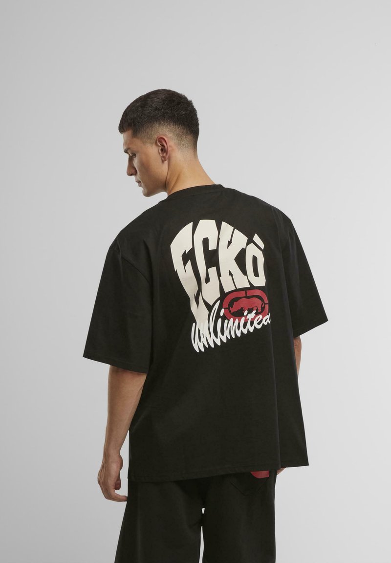 Black short-sleeve t-shirt featuring large white text reading "FCKØ Unlimited" and a red lips graphic on the back. Relaxed fit design.