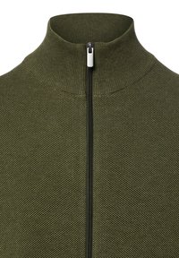 Groene textuurtrui met ritssluiting en hoge kraag; voorzien van een zwarte rits en geribbelde details rondom de hals en het lichaam.