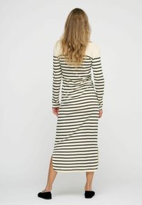 Langärmliges, gestreiftes Kleid in Creme und Dunkelgrün mit seitlichen Schlitzen, aus weichem Stoff gefertigt. Es hat eine taillierte Silhouette und einen runden Ausschnitt.